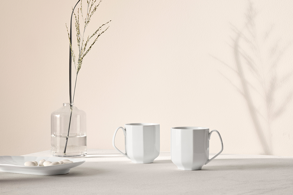 To smukke krus i Hvid Facet står på et hvidt bord og kaster skygger op på en hvid væg